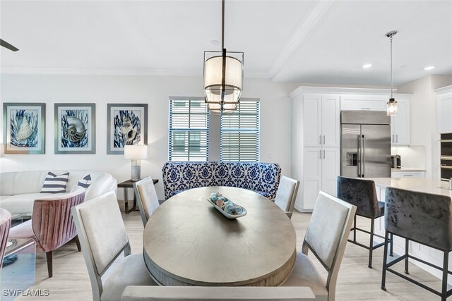 dining area featuring light hardwood / wood-style flooring, ornamental molding, and an inviting chandelier