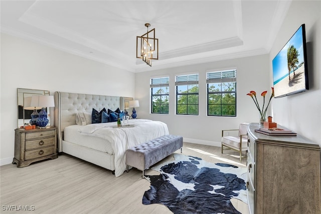 bedroom featuring a tray ceiling, an inviting chandelier, and light hardwood / wood-style floors