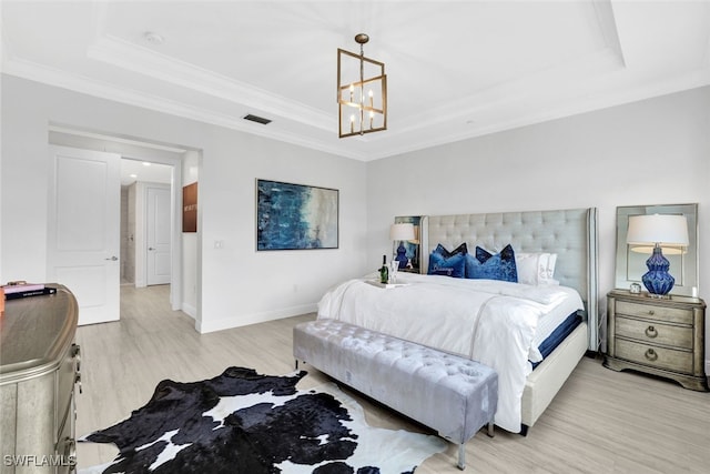 bedroom featuring a chandelier, a raised ceiling, ornamental molding, and light hardwood / wood-style flooring