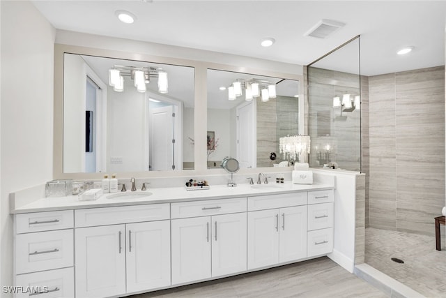 bathroom with a tile shower and vanity