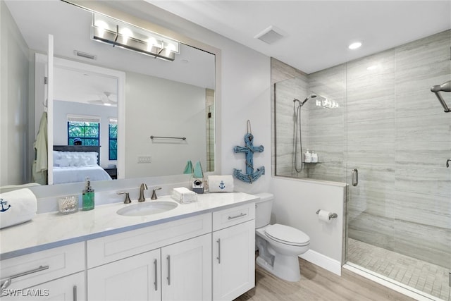 bathroom with wood-type flooring, vanity, toilet, and a shower with door