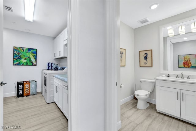 bathroom with wood-type flooring, vanity, toilet, and washing machine and clothes dryer