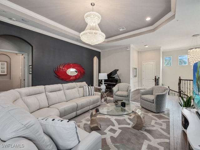 living room with crown molding, hardwood / wood-style flooring, an inviting chandelier, and a raised ceiling