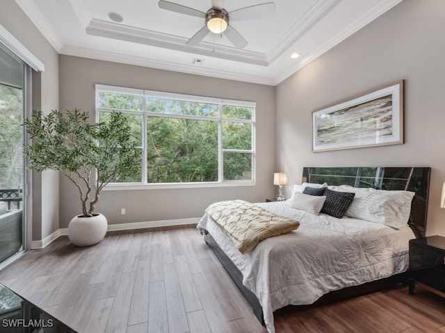 bedroom with light hardwood / wood-style floors, ornamental molding, a tray ceiling, and ceiling fan