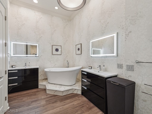 bathroom featuring vanity, crown molding, wood-type flooring, and a washtub