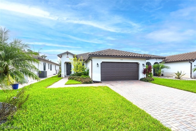 mediterranean / spanish-style home with a front lawn, central AC unit, and a garage