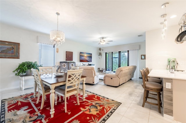 dining space with sink, light tile patterned flooring, and ceiling fan with notable chandelier