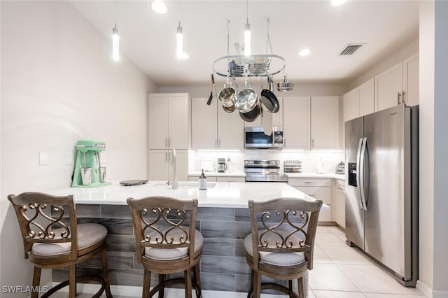 kitchen with a kitchen bar, appliances with stainless steel finishes, white cabinetry, and an island with sink