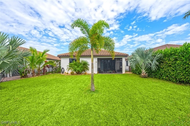 rear view of property featuring a lawn and a sunroom