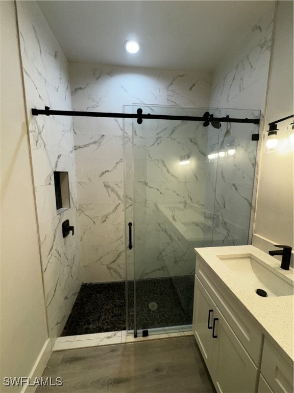 bathroom featuring hardwood / wood-style flooring, a shower with door, and vanity