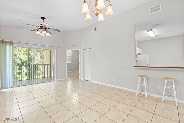 empty room with ceiling fan with notable chandelier, light tile patterned flooring, and lofted ceiling