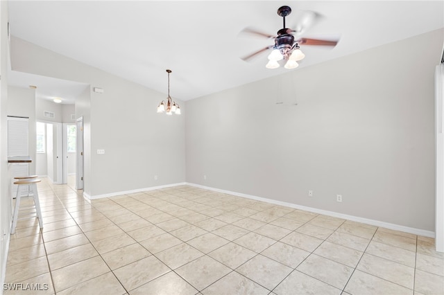 tiled empty room with ceiling fan with notable chandelier and vaulted ceiling