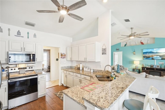 kitchen with visible vents, open floor plan, a peninsula, stainless steel appliances, and a sink