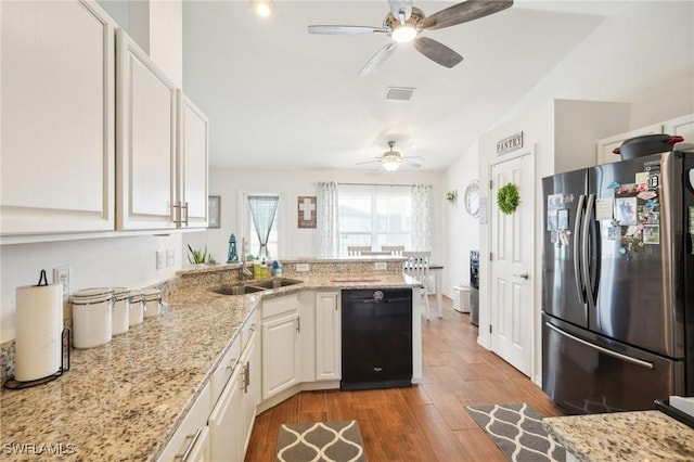 kitchen featuring wood finished floors, dishwasher, a peninsula, and freestanding refrigerator