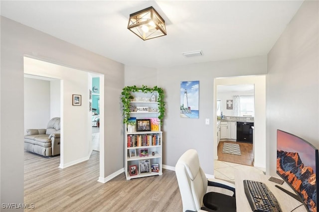 home office with light wood-type flooring, baseboards, and visible vents