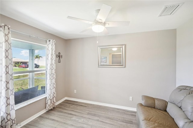 sitting room featuring a ceiling fan, baseboards, visible vents, and light wood finished floors