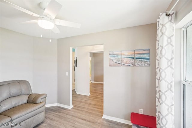 sitting room featuring light wood-type flooring, baseboards, and a ceiling fan