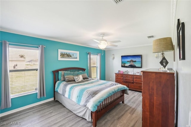 bedroom featuring a ceiling fan, wood finished floors, baseboards, and ornamental molding