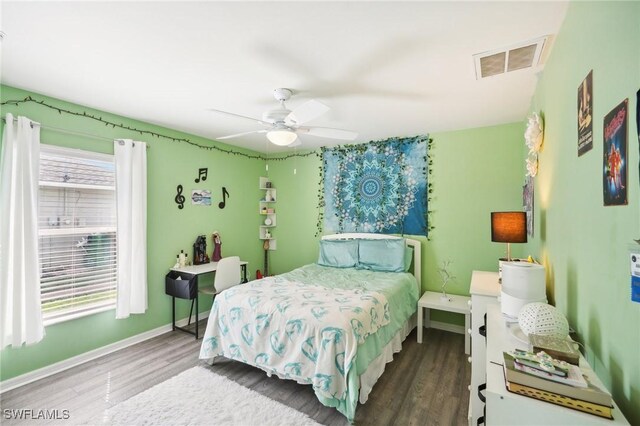 bedroom with ceiling fan, wood finished floors, visible vents, and baseboards