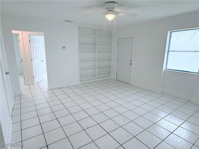 unfurnished room with built in features, ceiling fan, and light tile patterned floors