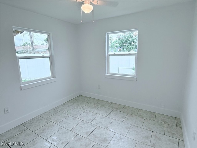 tiled spare room featuring ceiling fan and a healthy amount of sunlight