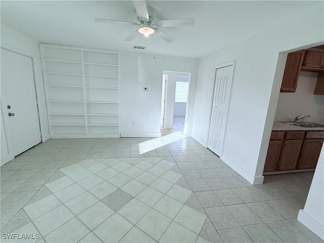 empty room with sink, ceiling fan, and light tile patterned floors