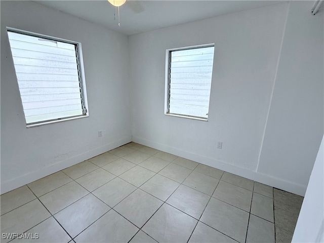 tiled spare room featuring ceiling fan