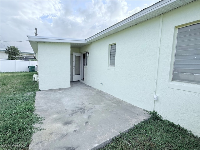 view of side of home with a lawn and a patio