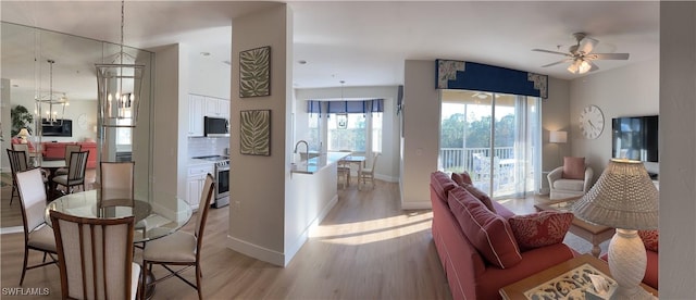 living room featuring ceiling fan, light wood-type flooring, and sink