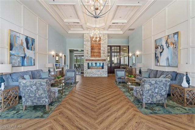 living room featuring a stone fireplace, crown molding, a chandelier, and a high ceiling