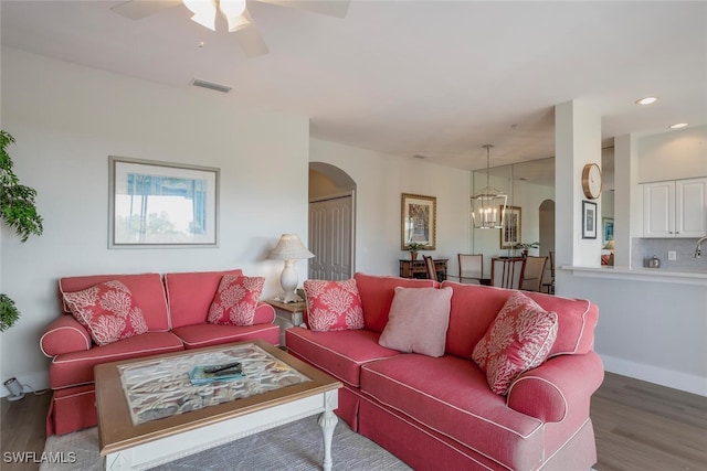 living room featuring wood-type flooring and ceiling fan with notable chandelier