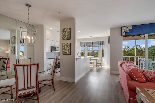 interior space with light hardwood / wood-style flooring, ceiling fan with notable chandelier, and sink