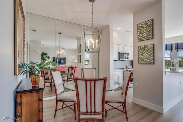 dining area with light wood-type flooring and a notable chandelier