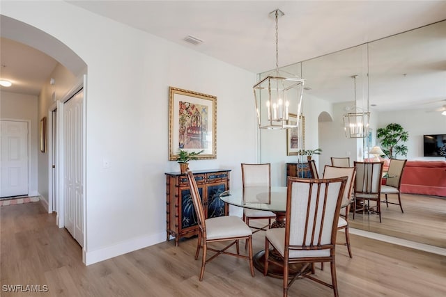 dining area featuring ceiling fan with notable chandelier and light wood-type flooring