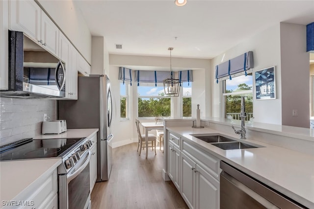 kitchen featuring white cabinetry, sink, stainless steel appliances, tasteful backsplash, and light hardwood / wood-style flooring