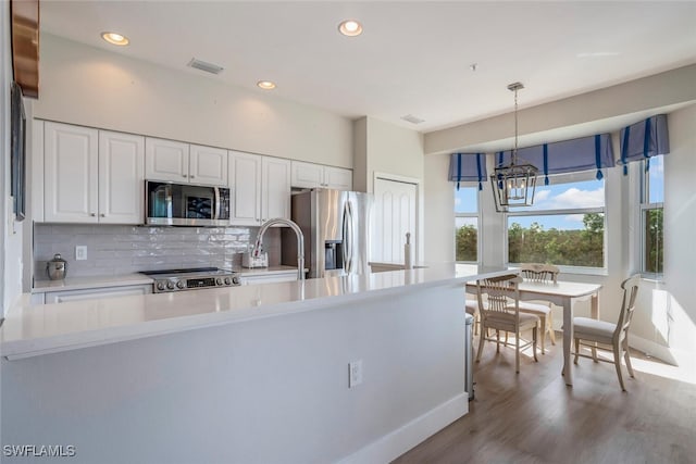 kitchen with pendant lighting, sink, appliances with stainless steel finishes, light hardwood / wood-style floors, and white cabinetry