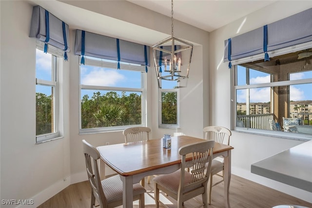 dining space with wood-type flooring, a wealth of natural light, and a chandelier