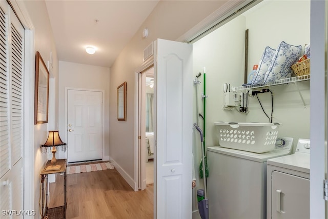 laundry area with washing machine and clothes dryer and light hardwood / wood-style flooring