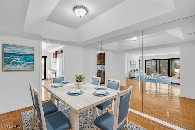 dining space featuring parquet flooring and a tray ceiling