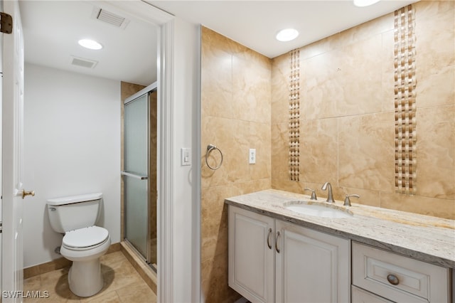 bathroom featuring toilet, tile patterned flooring, vanity, tile walls, and an enclosed shower