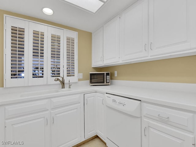 kitchen featuring white dishwasher, sink, and white cabinetry