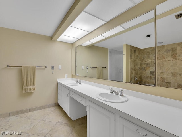 bathroom with a shower with door, vanity, and tile patterned floors