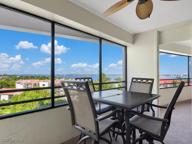 sunroom featuring a healthy amount of sunlight, a water view, and ceiling fan