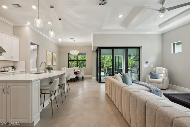 living room featuring ornamental molding, ceiling fan, and sink