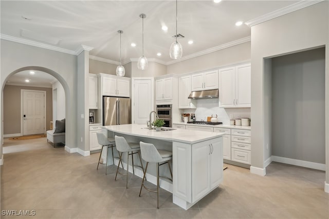 kitchen featuring pendant lighting, a center island with sink, ornamental molding, appliances with stainless steel finishes, and white cabinetry