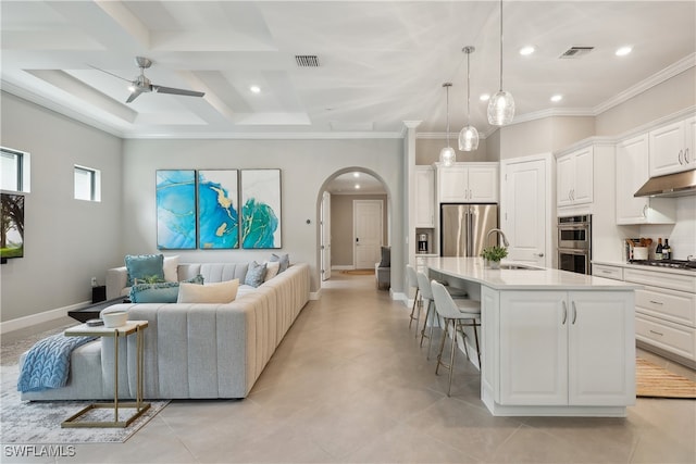 kitchen with pendant lighting, a kitchen island with sink, white cabinetry, appliances with stainless steel finishes, and a kitchen breakfast bar