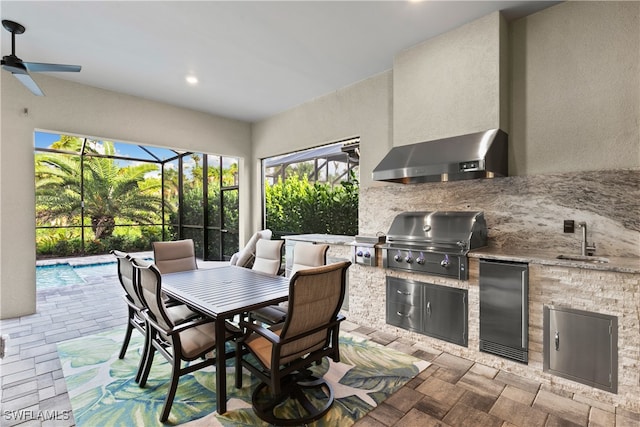 view of patio / terrace featuring ceiling fan, area for grilling, sink, glass enclosure, and an outdoor kitchen