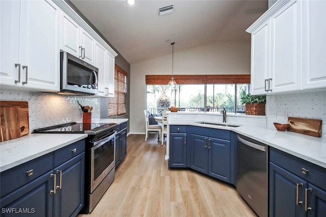 kitchen with blue cabinets, white cabinets, sink, stainless steel appliances, and vaulted ceiling