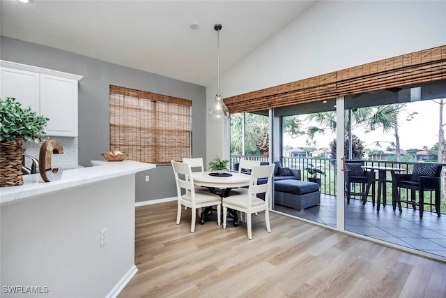 dining room featuring light wood-type flooring and high vaulted ceiling