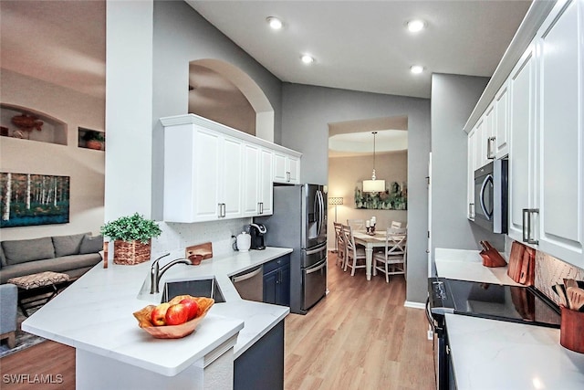 kitchen with lofted ceiling, kitchen peninsula, tasteful backsplash, white cabinetry, and appliances with stainless steel finishes